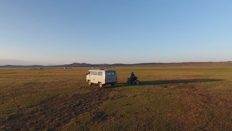 Luftdrohnenaufnahme-Bei-Sonnenaufgang-Eines-Motorrads-Und-Eines-Russischen-Lieferwagens-In-Der-Mongolischen-Steppe